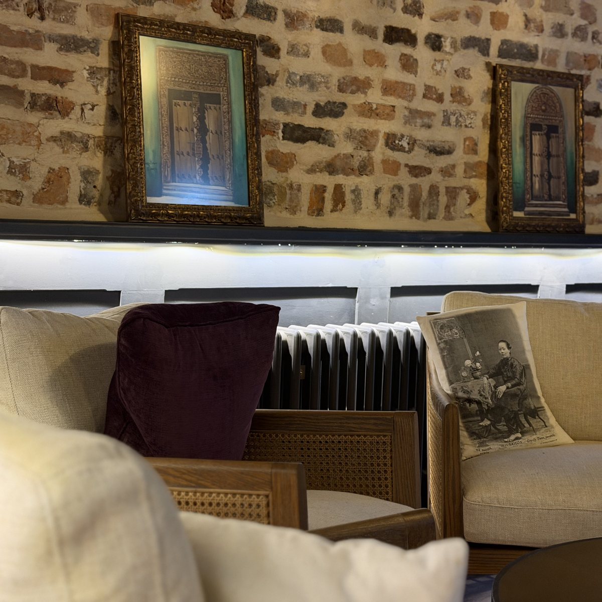 Concealed LED strip lighting the banquette and framed artwork on exposed brick