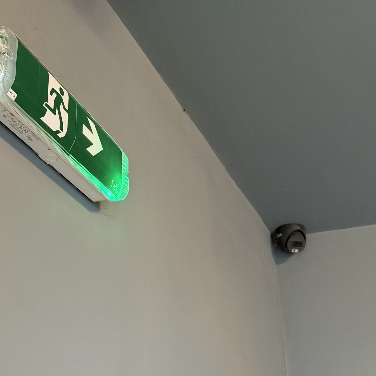 Maintained emergency exit sign and CCTV camera at the head of the stairs