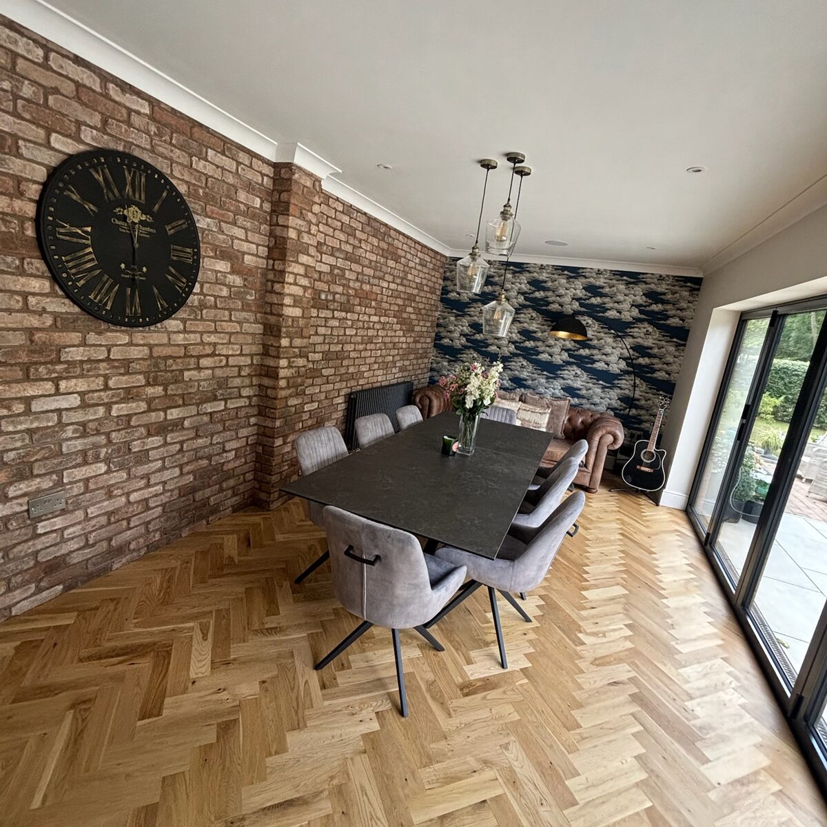 Dining area with feature pendants, parquet floor and exposed brick